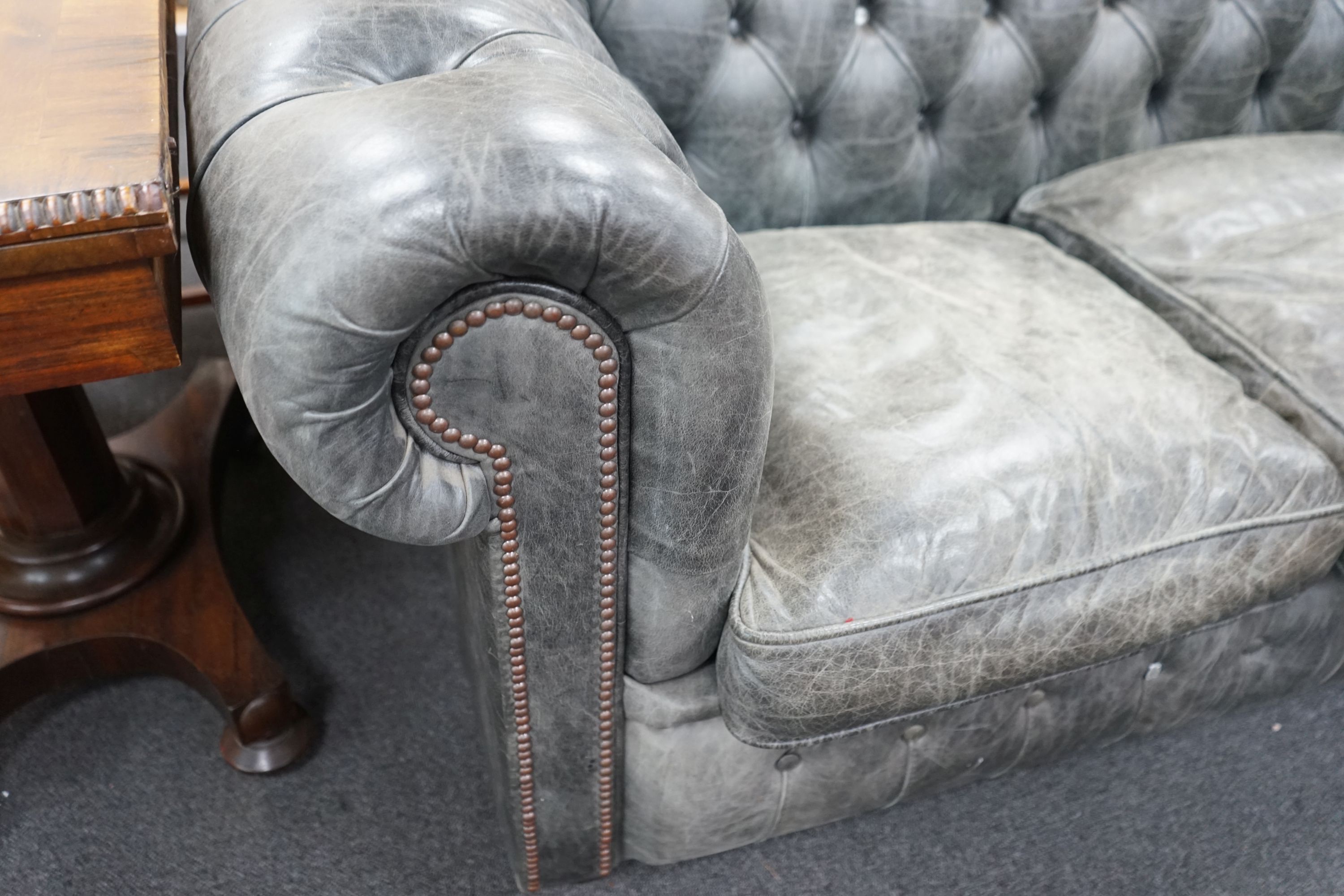 A deep buttoned faded black leather Chesterfield three seater settee, length 210cm, depth 90cm, height 78cm